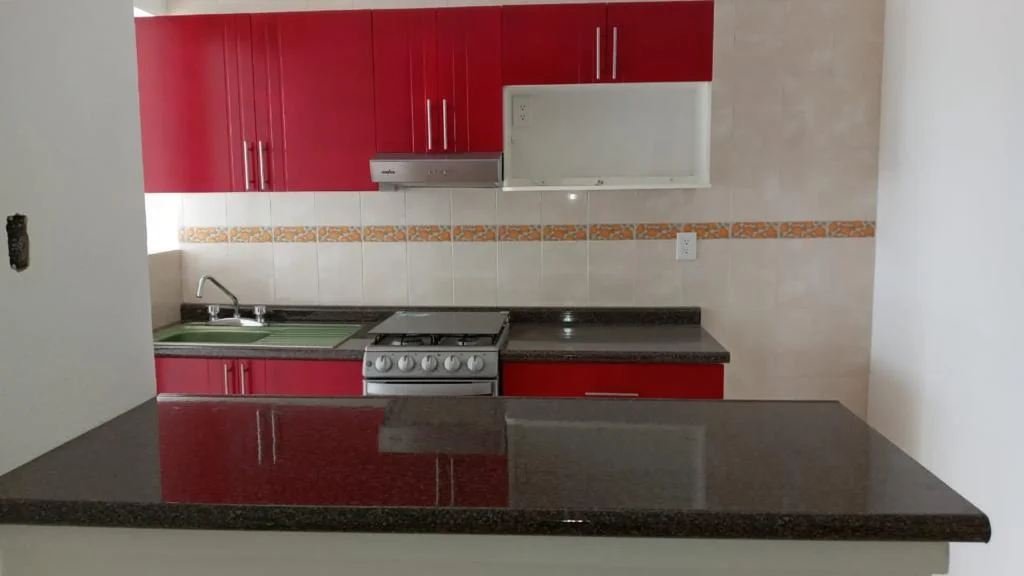 Cocina con gabinetes rojos y barra de granito